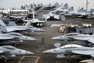A US Navy officer walks past fighter jets sitting on the flight deck of the Nimitz-class aircraft carrier USS Abraham Lincoln during a media tour in Port Klang, on the outskirts of Kuala Lumpur, on November 26, 2024